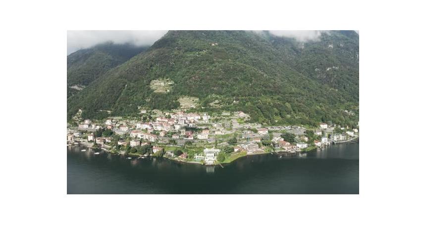 A tilting drone shot that captures a famous villa beneath a formidable, cloud covered mountain on th