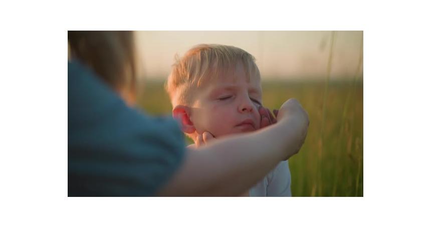 CloseUp of a Mother Gently Wiping Her Son's Face Outdoors