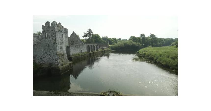 Ruins of Adare Castle overlooking calm river Maigue on a sunny day in Limerick, Ireland