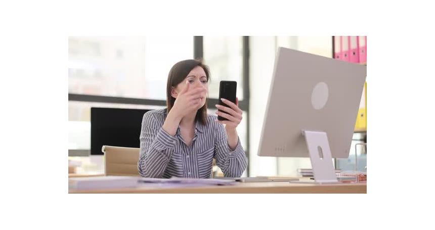 Woman Reacts to Shocking News on Phone in Office